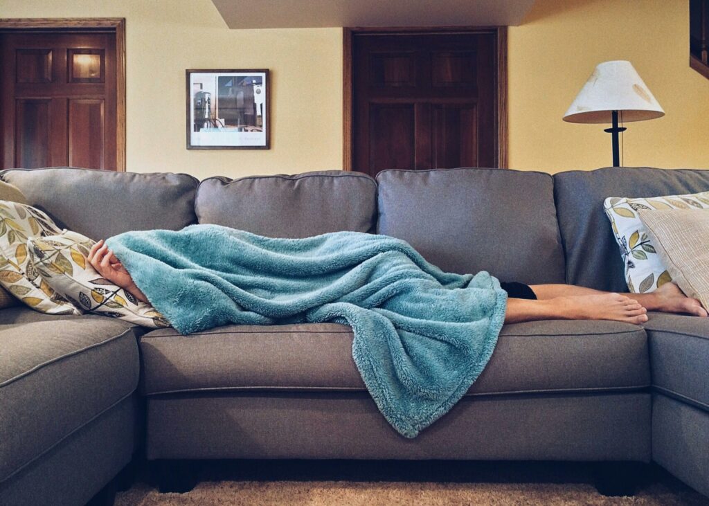 person laying on couch under a blanket